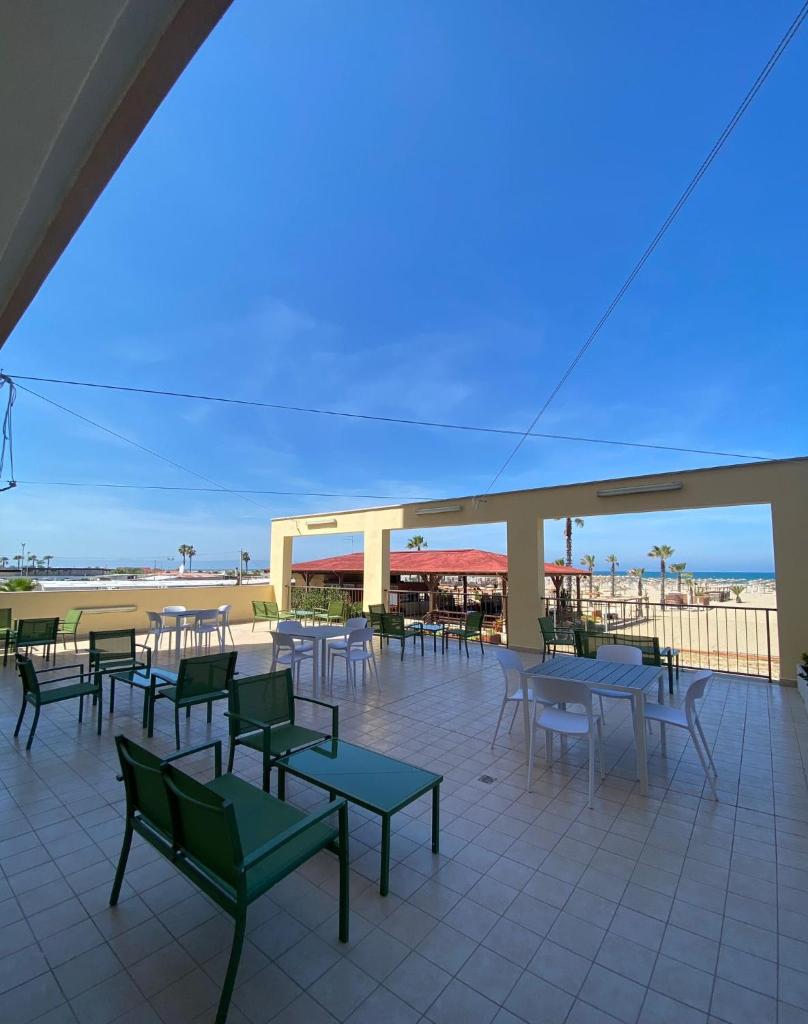 un patio avec des tables et des chaises avec une plage en arrière-plan dans l'établissement Lbr SUITE Apartment, à Margherita di Savoia