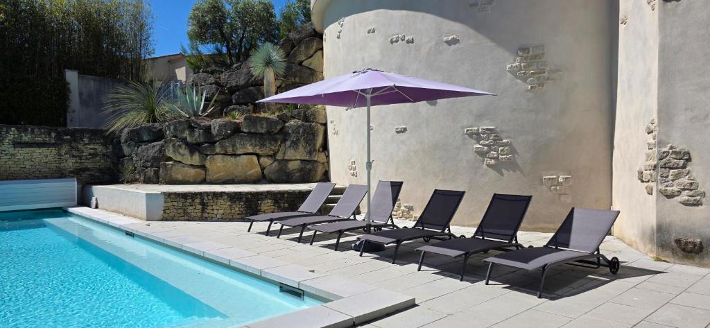 - un groupe de chaises avec un parasol à côté de la piscine dans l'établissement Gîte Charmant avec Piscine et Terrasse en Provence MDV, à Carpentras