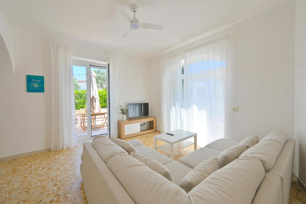 - un salon blanc avec un grand canapé blanc dans l'établissement Villa Maddalena Ischia Giardino Privato e Parcheggio - Perfetta per 6 Ospiti, à Ischia