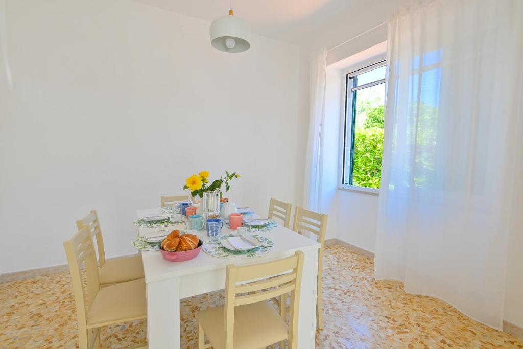 une salle à manger avec une table blanche et une fenêtre dans l'établissement Villa Maddalena Ischia Giardino Privato e Parcheggio - Perfetta per 6 Ospiti, à Ischia