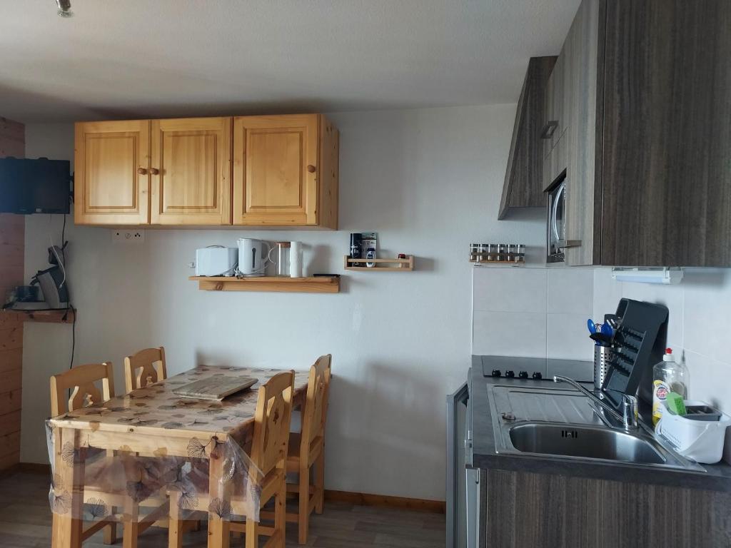 - une cuisine avec une table en bois, des chaises et un évier dans l'établissement Le Rhodo, à Thollon-les-Mémises