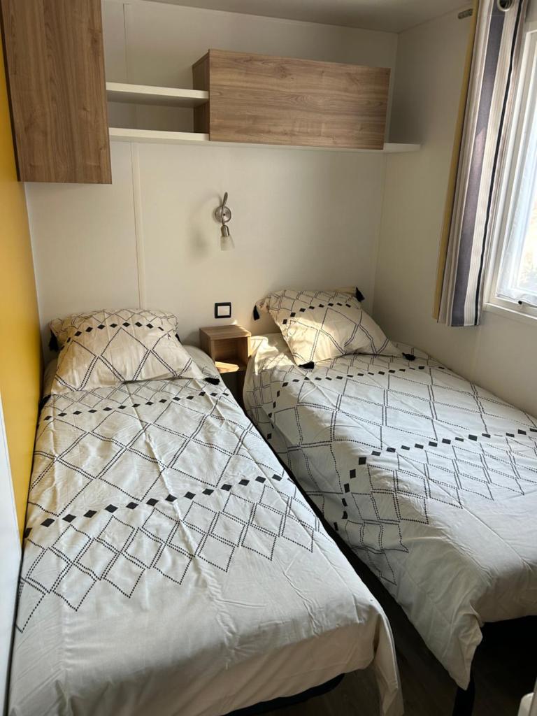 deux lits côte à côte dans une chambre dans l'établissement Mobilhome Landes Les Dunes de Contis, à Saint-Julien-en-Born 32 autres photos
