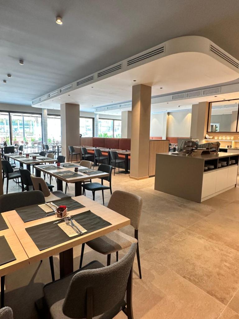 un restaurant avec des tables et des chaises et une cuisine dans l'établissement Petit Hotel, à Caorle