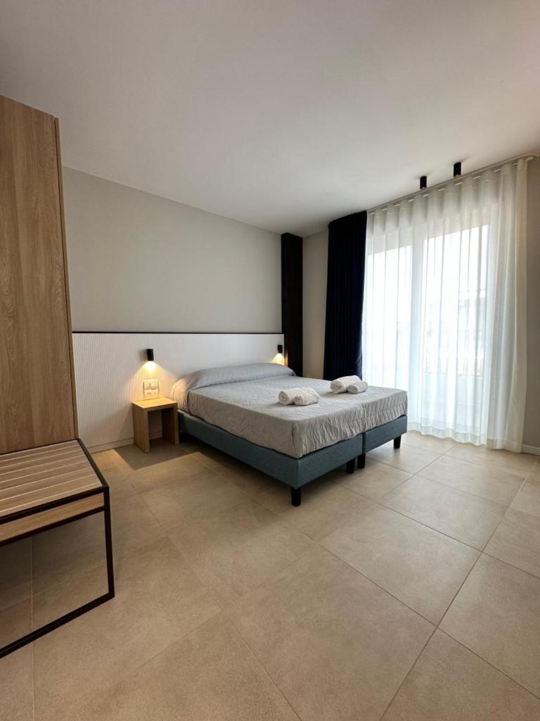 une chambre avec un lit et une grande fenêtre dans l'établissement Petit Hotel, à Caorle