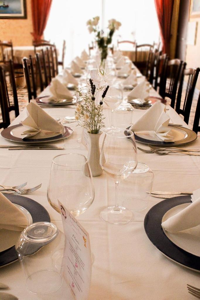 - une longue table avec des assiettes et des verres à vin dans l'établissement Hotel Corallo, à Villapiana