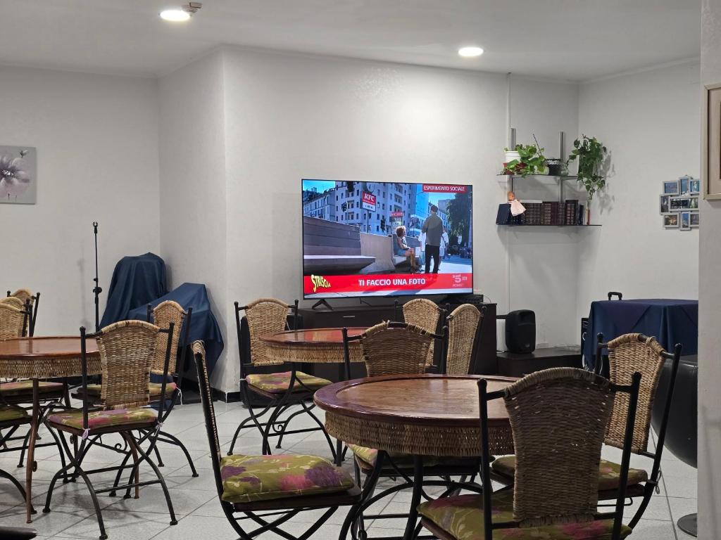 Cette chambre dispose de tables, de chaises et d'une télévision à écran plat. dans l'établissement Gargano Hotel Helios, à Rodi Garganico