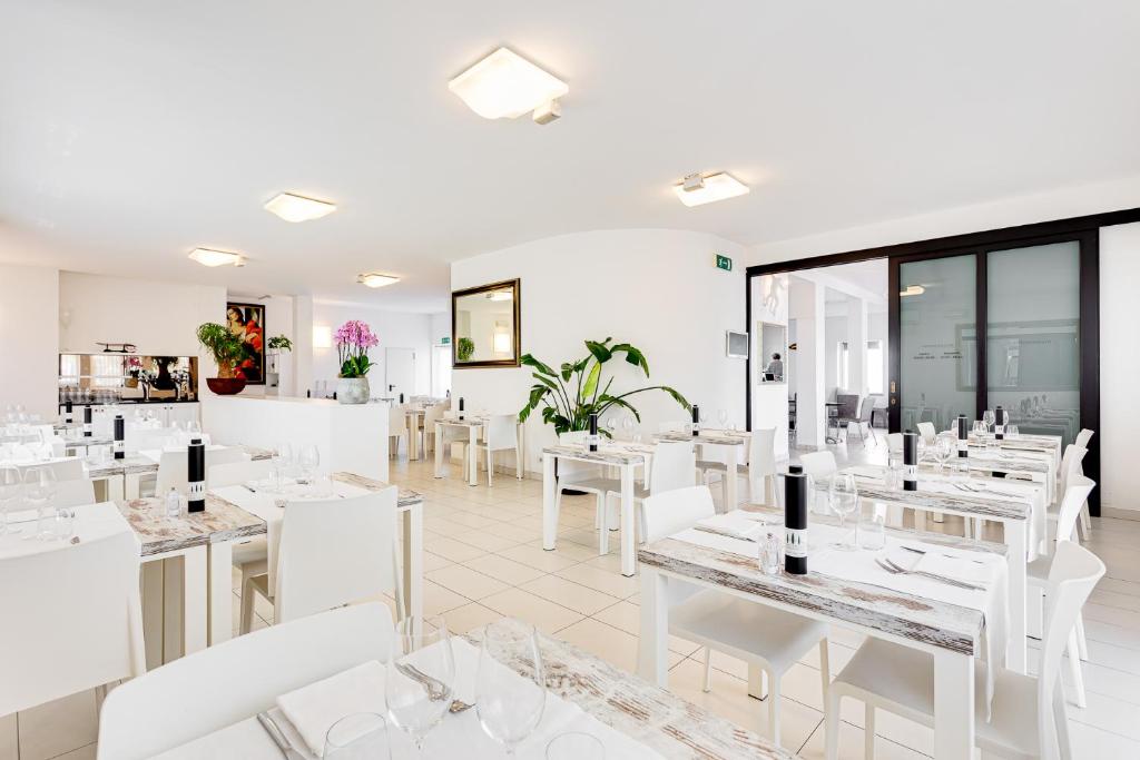 un restaurant blanc avec des tables blanches et des chaises blanches dans l'établissement Hotel Blues, à Cervia
