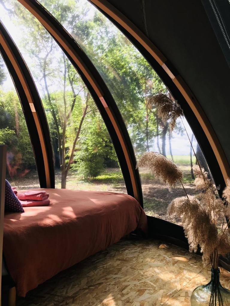 un lit dans une pièce ronde avec une grande fenêtre dans l'établissement Ô cocon del Lauragués, à Ricaud