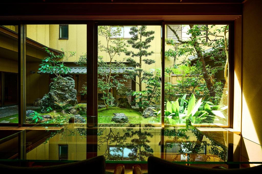 une fenêtre avec vue sur un jardin à l'extérieur d'un bâtiment dans l'établissement Yamatoya Besso, à Matsuyama