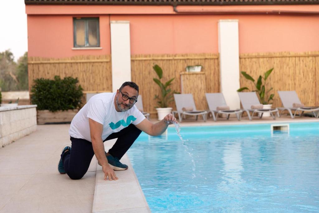 un homme déverse de l'eau dans une piscine dans l'établissement Villa Covile, à Casarano