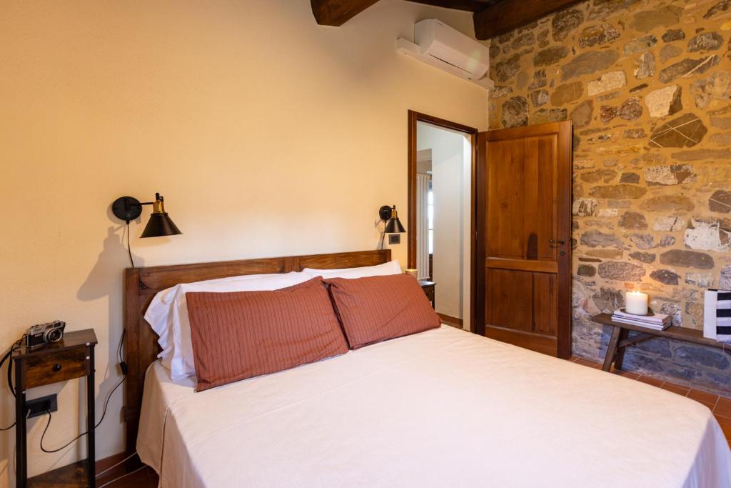 une chambre avec un lit et un mur en pierre dans l'établissement PODERE SAN LORENZO 12, Emma Villas, à Celle sul Rigo 24 autres photos