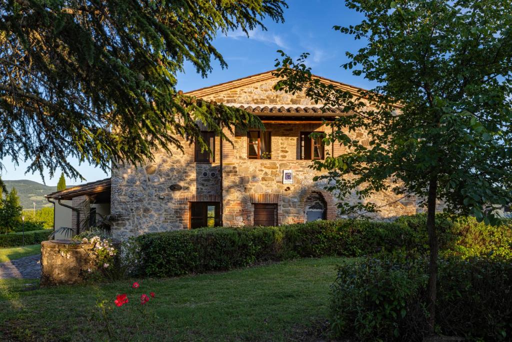 une maison en pierre avec un arbre devant dans l'établissement PODERE SAN LORENZO 12, Emma Villas, à Celle sul Rigo