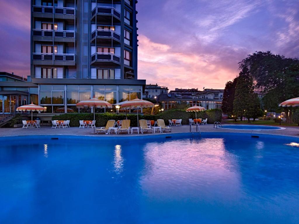 une grande piscine avec des chaises et des parasols en face d'un bâtiment dans l'établissement Hotel Le Tegnue, à Sottomarina