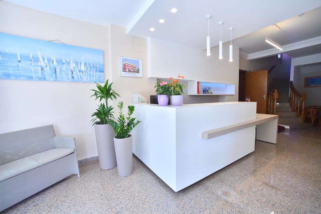 un hall d'entrée avec un comptoir blanc avec des plantes en pot dans l'établissement Hotel Di Giovanni, à Bibione 36 autres photos