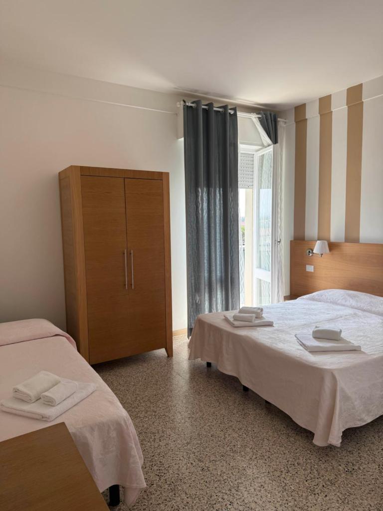 - une chambre d'hôtel avec 2 lits et une commode dans l'établissement Hotel Gin sul mare, à Rimini