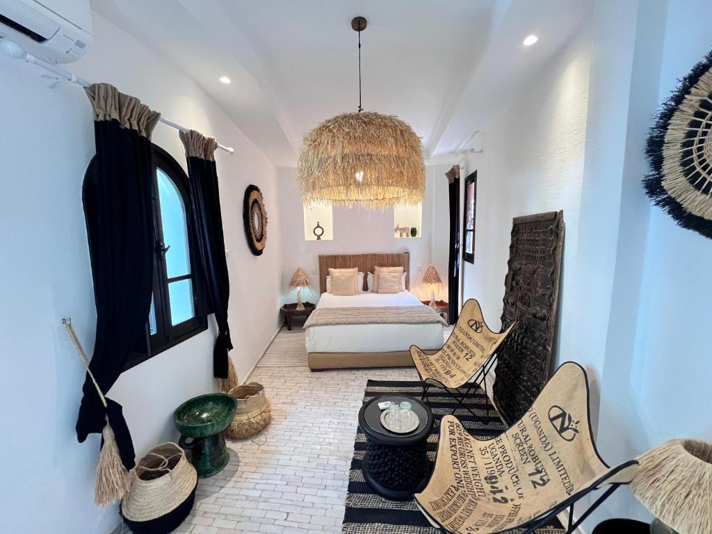 une chambre avec un lit et des chaises dans une pièce dans l'établissement Riad Al Rimal & Spa, à Marrakech