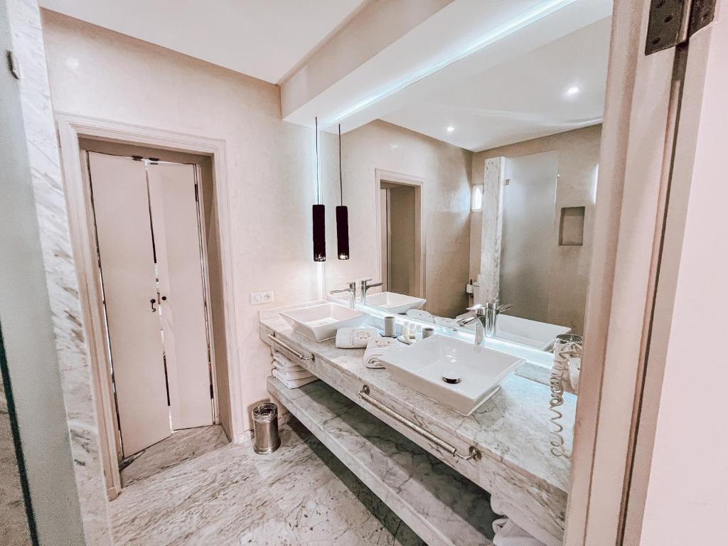 une salle de bain avec deux lavabos et un grand miroir dans l'établissement Riad Al Rimal & Spa, à Marrakech