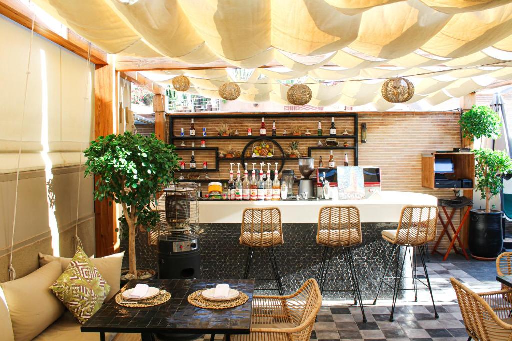 un patio avec une table, des chaises et un bar dans l'établissement Riad Al Rimal & Spa, à Marrakech
