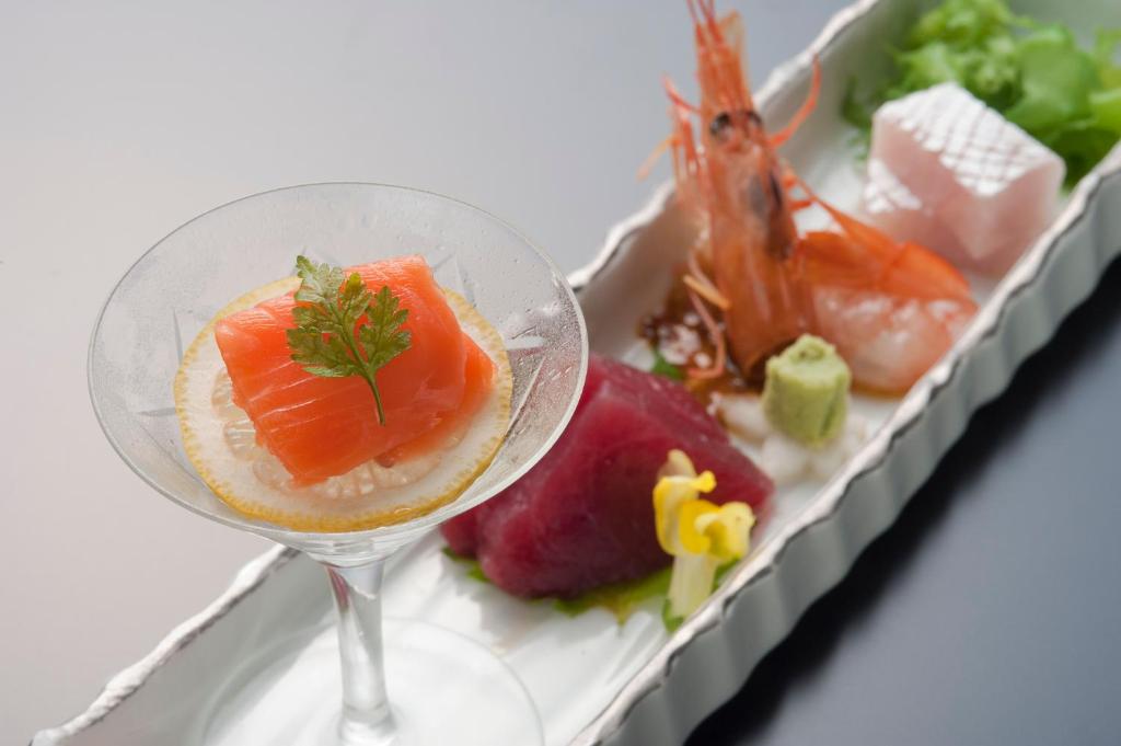 une assiette de nourriture accompagnée d'un verre de vin avec du poisson dans l'établissement かっぱの宿旅館三治郎, à Zao