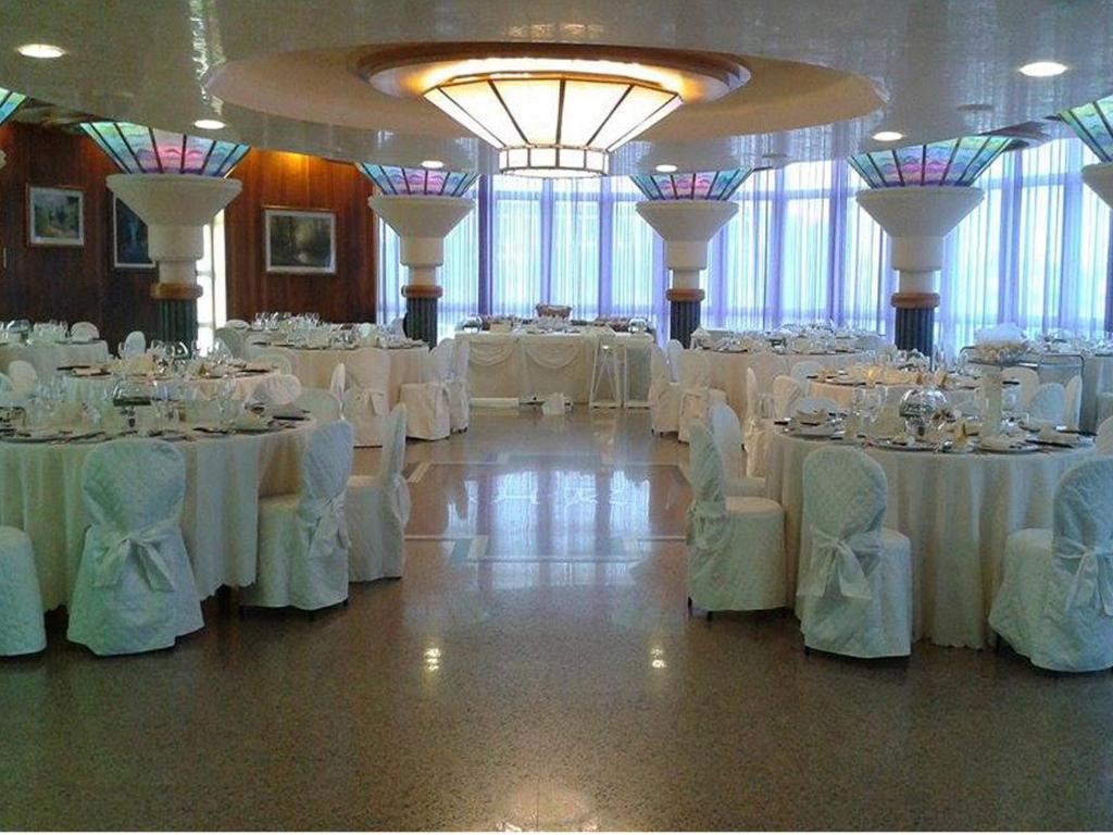 une salle de banquet avec des tables et des chaises blanches dans l'établissement Hotel Le Tegnue, à Sottomarina 79 autres photos