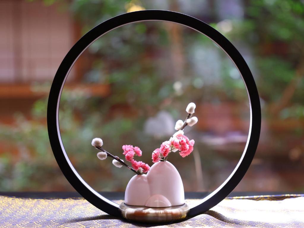 un miroir avec un vase rose contenant des fleurs dans l'établissement Hamanoyu, à Suwa