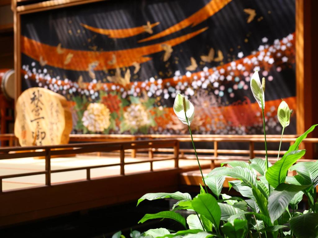 une pièce avec un grand tableau en arrière-plan avec une plante dans l'établissement Hamanoyu, à Suwa