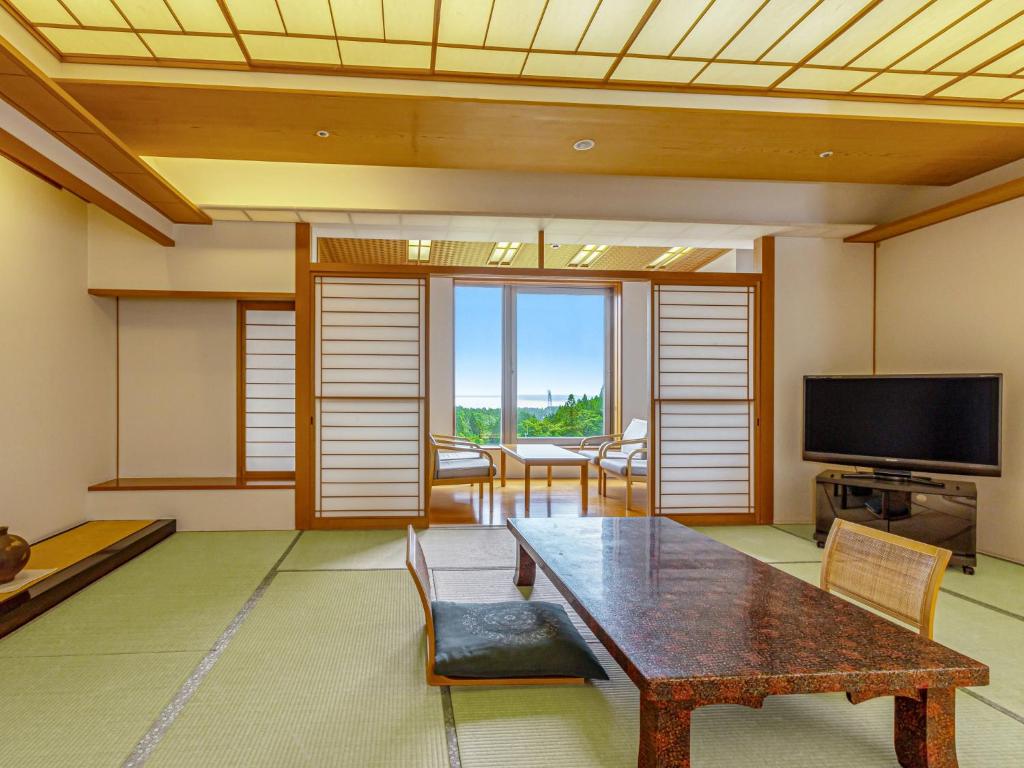 un salon avec une table et une télévision dans l'établissement KAMENOI HOTEL Aomori Makado, à Noheji
