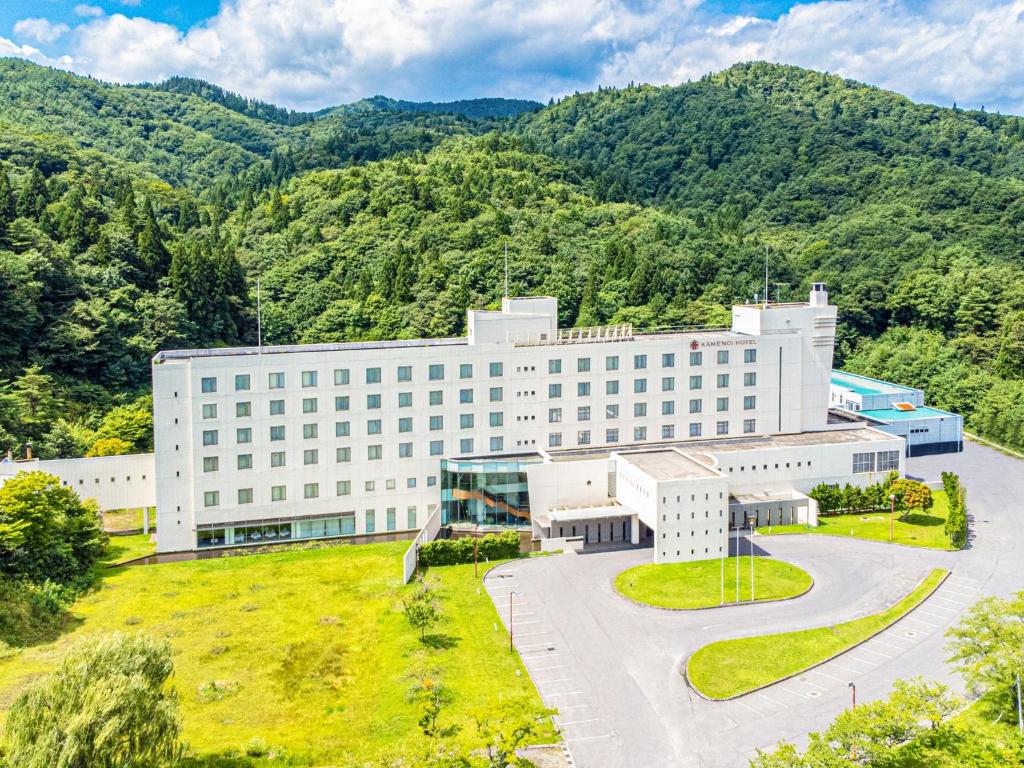 Vue de tête d'un bâtiment avec des montagnes en arrière-plan dans l'établissement KAMENOI HOTEL Aomori Makado, à Noheji