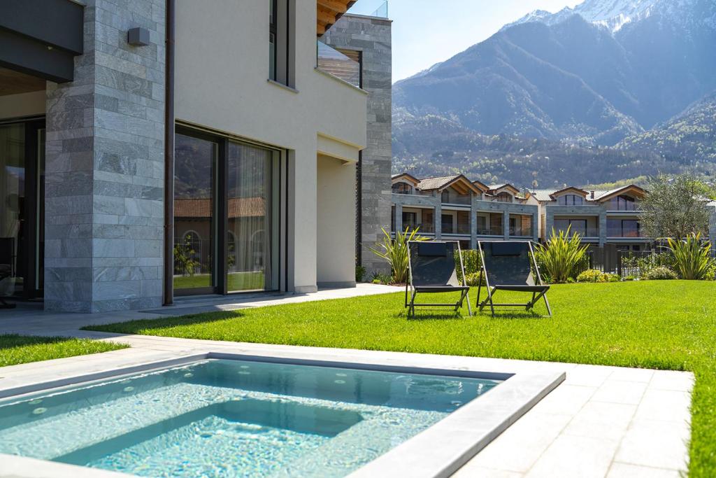 2 chaises assises dans l'herbe à côté d'une piscine dans l'établissement Villa Sabrina, à Colico