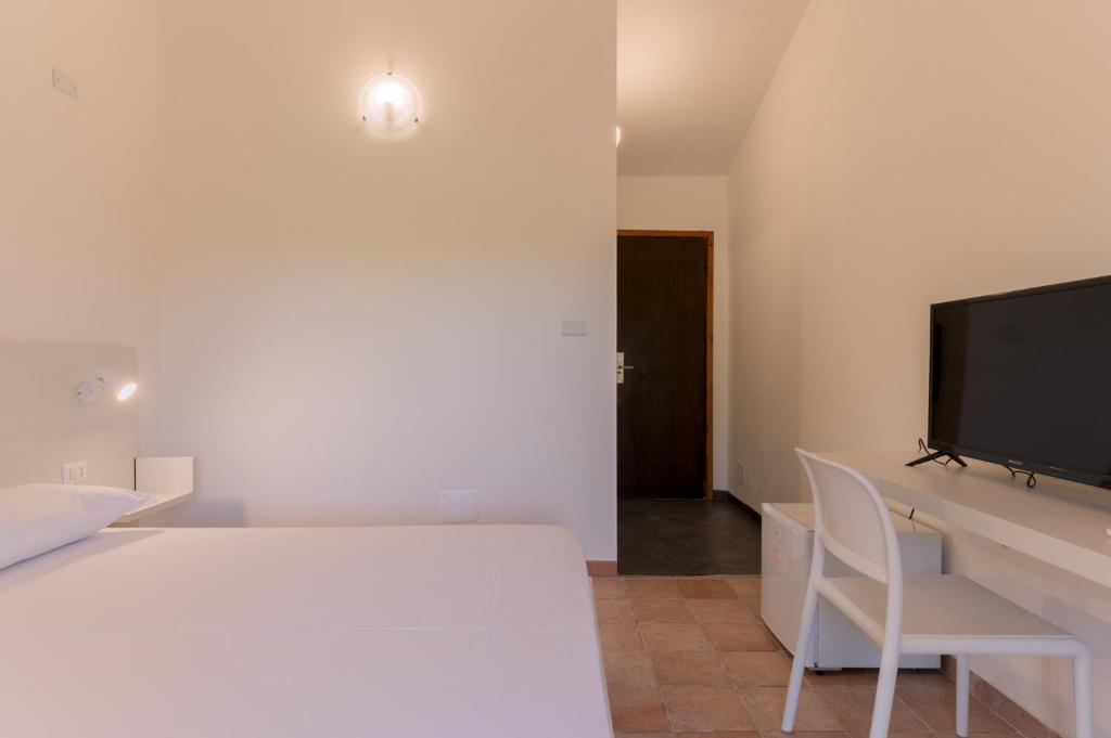 une chambre avec un lit blanc et une télévision dans l'établissement Q Resort, à Marina di Sorso