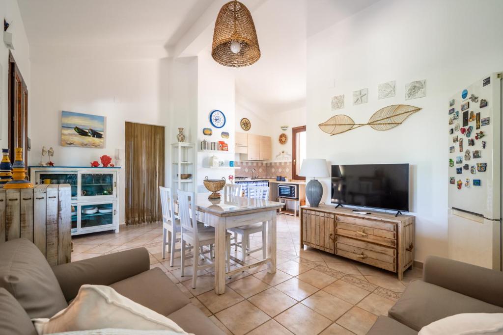 Il comprend une cuisine et un salon avec une table et une télévision. dans l'établissement VILLA HIBISCUS, à Castellammare del Golfo