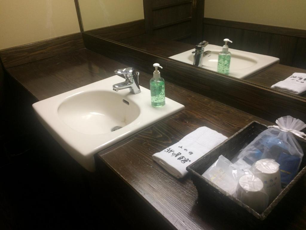 une salle de bain avec un lavabo et un miroir dans l'établissement Kurokawa Onsen Yama no Yado Shinmeikan, à Minamioguni