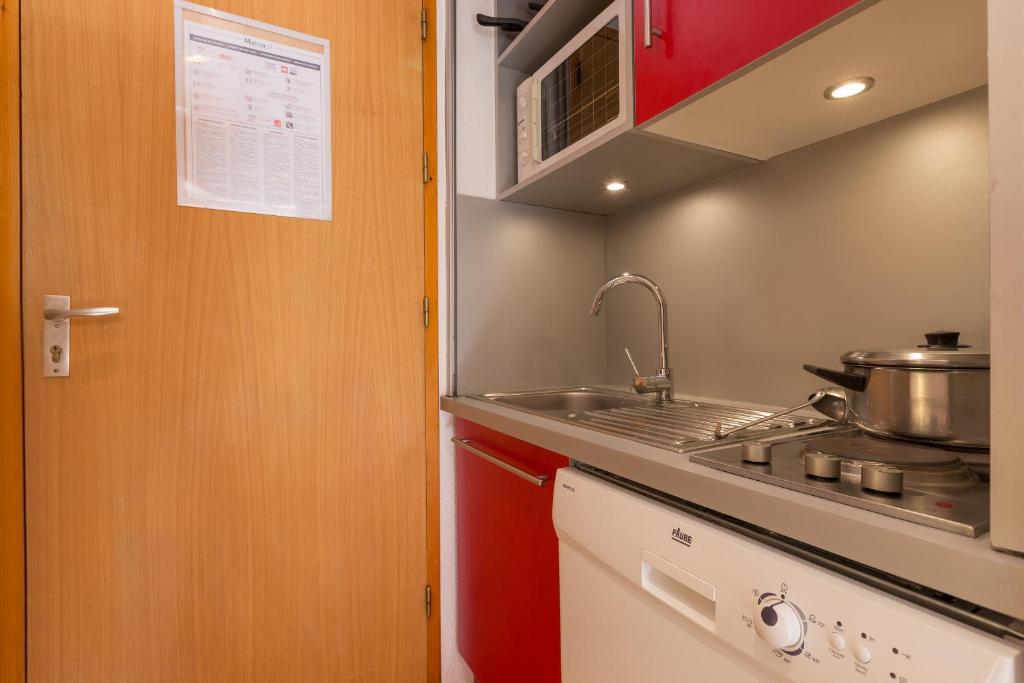 une petite cuisine avec un évier et une cuisinière dans l'établissement Résidence partenaire Le Golf, à Méribel