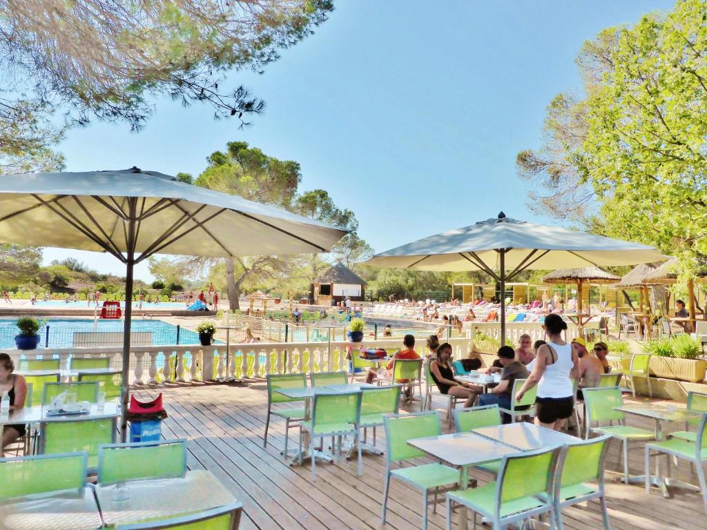 un groupe de personnes assises à des tables et des parasols dans l'établissement Carazur Mobilhomes Camping Fréjus, à Fréjus