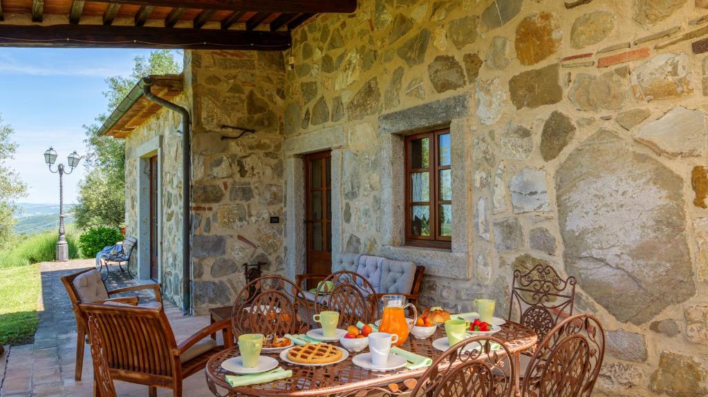 une maison en pierre avec une table et des chaises sur une terrasse dans l'établissement Montebendico 6, Emma Villas, à Castel del Piano