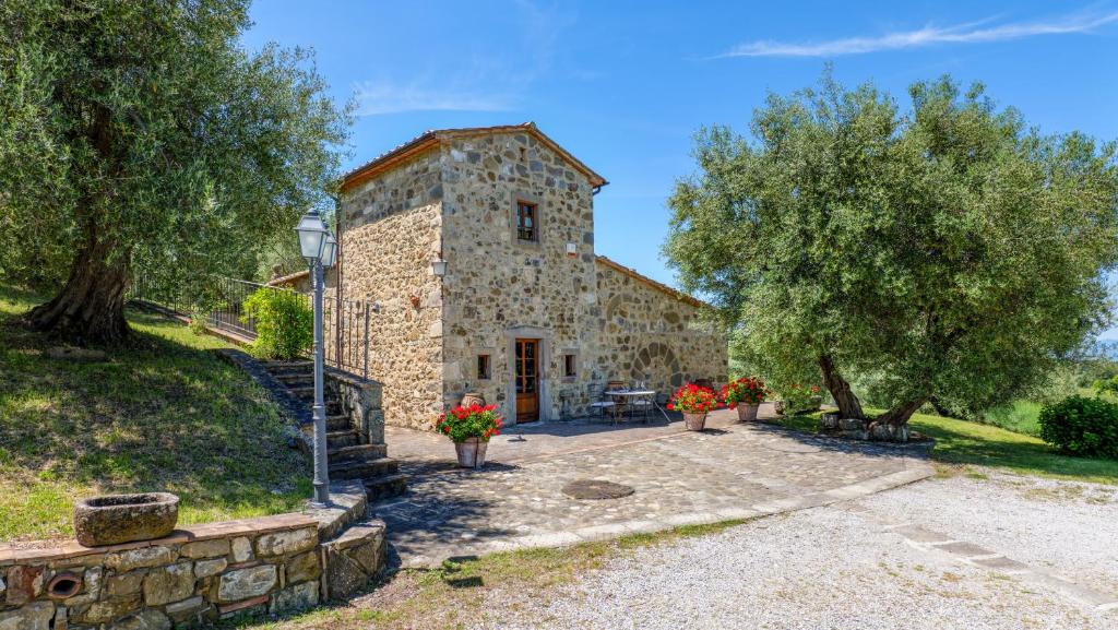 un vieux bâtiment en pierre avec des fleurs devant lui dans l'établissement Montebendico 6, Emma Villas, à Castel del Piano