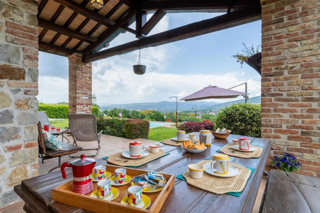 - une table avec des tasses et des assiettes de nourriture sur une terrasse dans l'établissement San Rocco 4, Emma Villas, à Montecchio