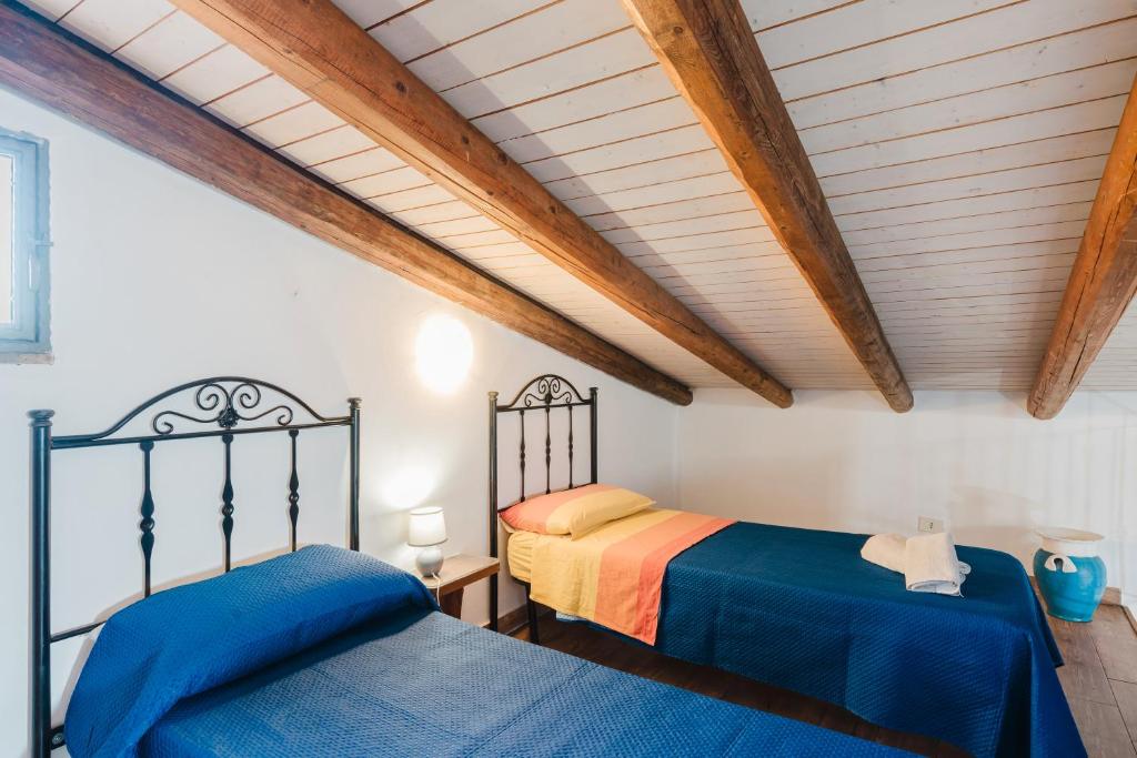 deux lits dans une chambre avec plafonds en bois dans l'établissement Casa Blandina, à Menfi