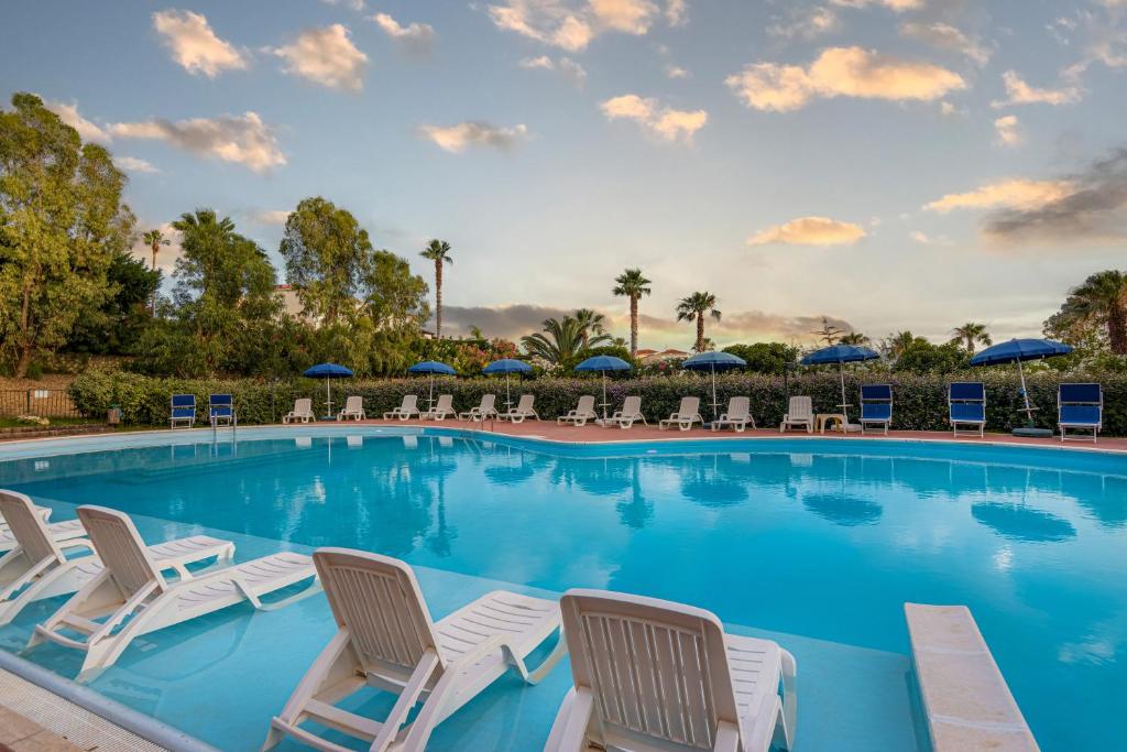 une grande piscine avec chaises et parasols dans l'établissement Residence Antigua, à Bonifati