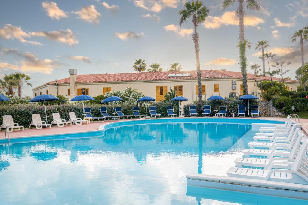 une piscine avec chaises longues et parasols dans l'établissement Residence Antigua, à Bonifati