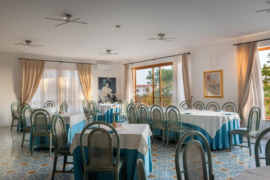 une salle à manger avec tables, chaises et fenêtres dans l'établissement Residence Antigua, à Bonifati