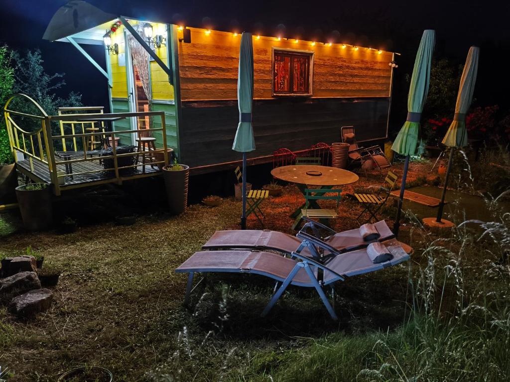 une terrasse avec une table et des chaises ainsi qu'une tente dans l'établissement La Ferme De Chenevier, La Roulotte Fleurie 2/4pers, à Saint-Victor