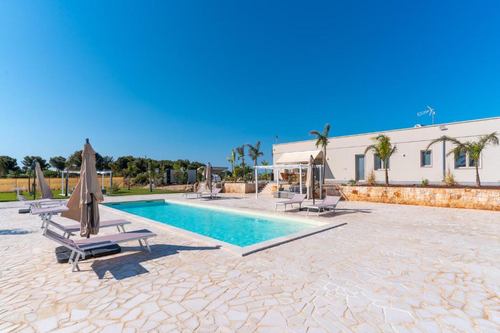 une piscine avec chaises et parasols à côté d'un bâtiment dans l'établissement Villa Red Wind by Perle di Puglia, à Nardò