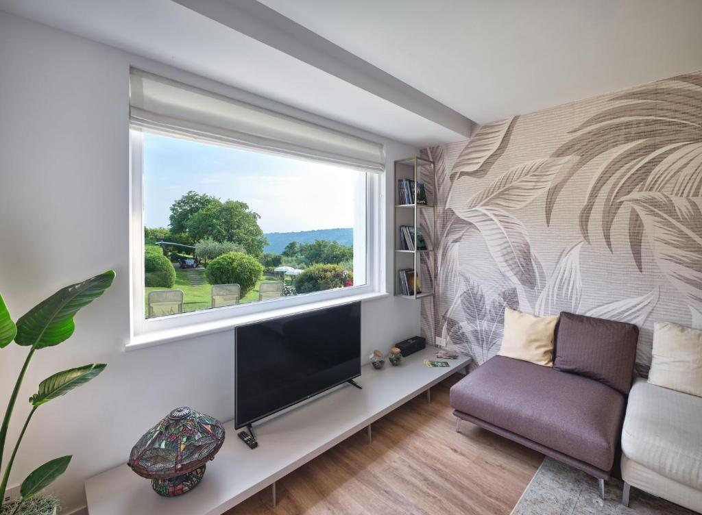 un salon avec une grande fenêtre et une télévision dans l'établissement Villa Beatrice, à Vérone
