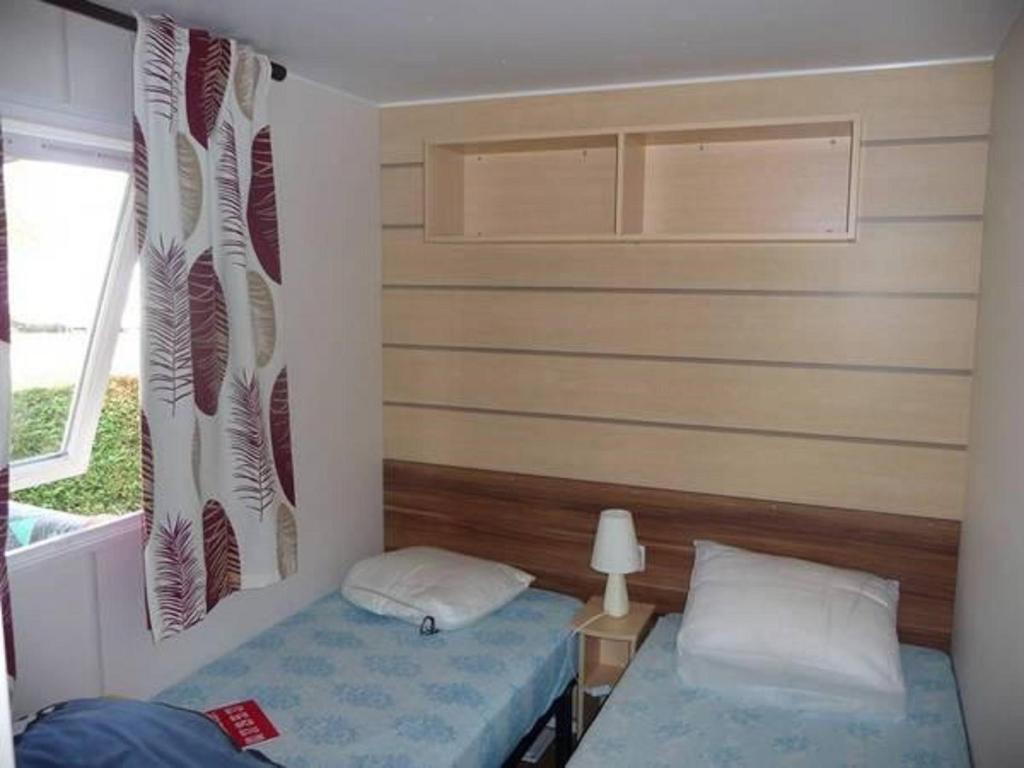 une petite chambre avec deux lits et une fenêtre dans l'établissement Mobil Home, à Saint-Jean-de-Monts