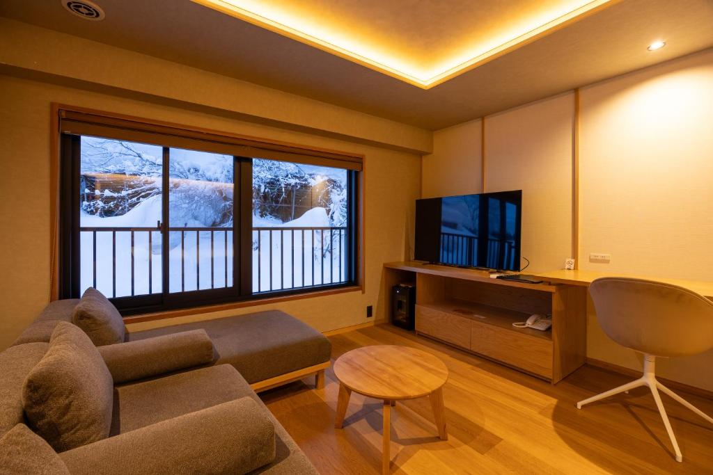 un salon avec un canapé et une télévision dans l'établissement Sake Hotel Tamakiya, à Tōkamachi