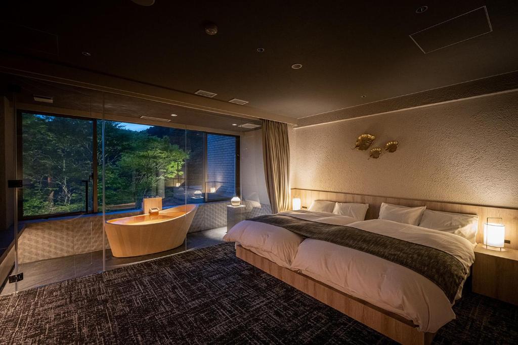 une chambre avec un grand lit et une grande fenêtre dans l'établissement Azumaen, à Unzen