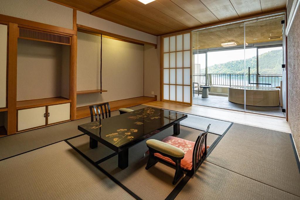 une salle à manger avec une table et des chaises et une grande fenêtre dans l'établissement Azumaen, à Unzen