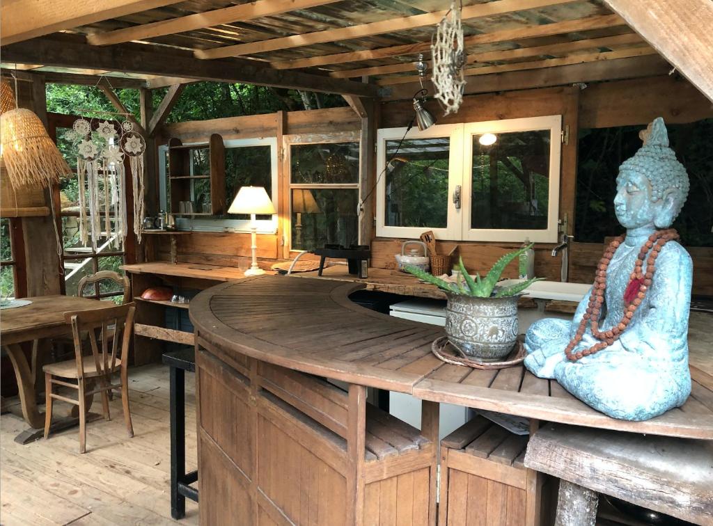une chambre avec une statue assise sur une table en bois dans l'établissement Yourte dans la forêt, à Rennes-les-Bains