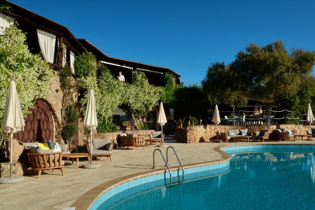 - une piscine avec des chaises et des parasols à côté d'un bâtiment dans l'établissement Hotel Don Diego, à Porto San Paolo